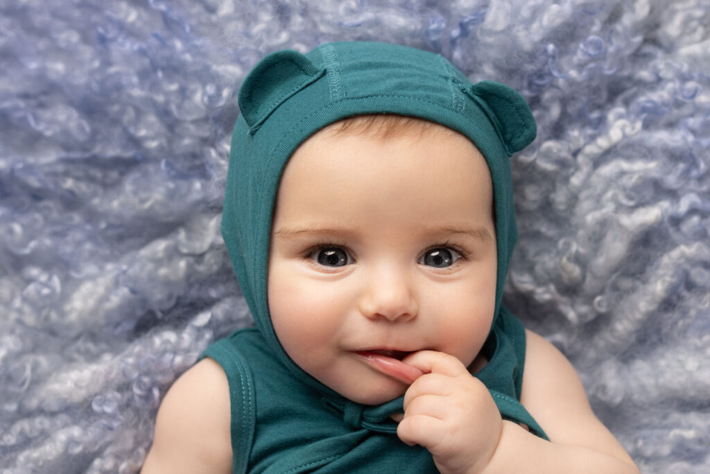 Studio portrait of a baby girl wearing a teal bonnet and matching outfit