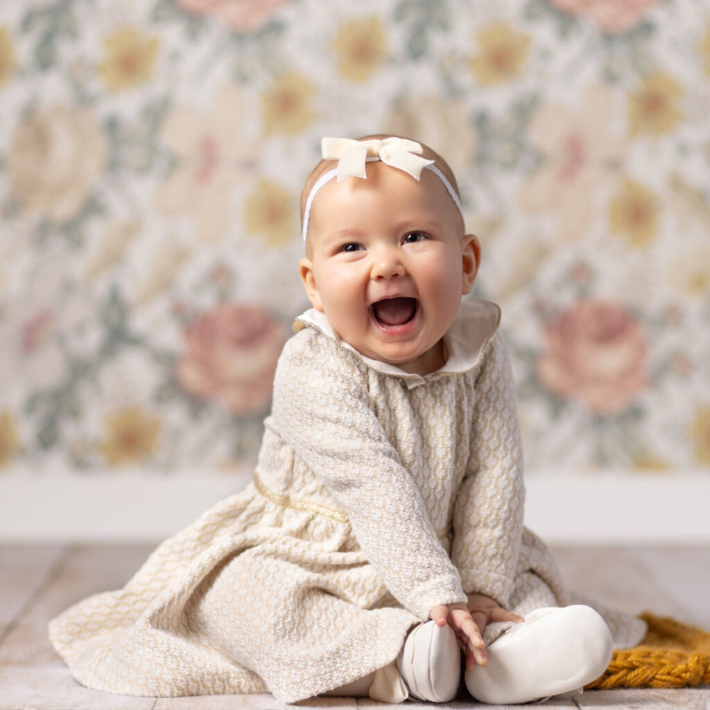 Smiling six-month-old baby girl sitting during milestone photography session