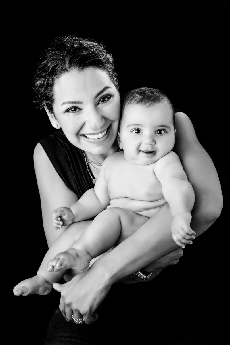 Smiling proud mother holding her baby during a black and white studio portrait session