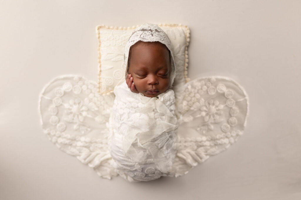 Sleeping newborn baby styled in a butterfly-inspired portrait setup