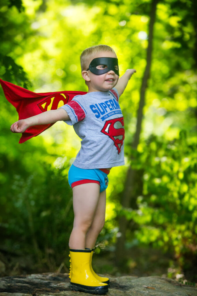 Young child dressed as superhero during outdoor portrait session.