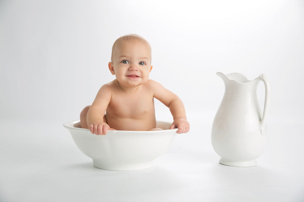 Six month old baby sitting in white porcelain bowl during milestone session