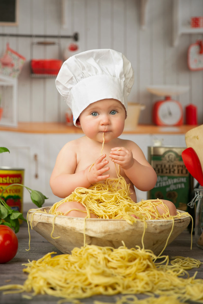One year old baby dressed as a chef eating spaghetti during a creative first birthday milestone photography session at Alternate Angles Photography in Norwood MA