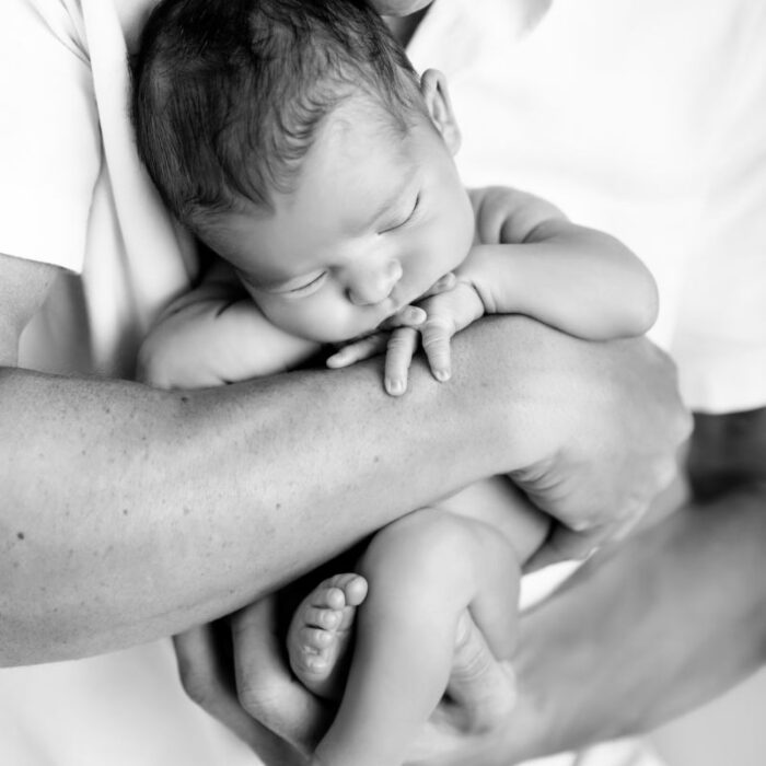Father holding sleeping newborn baby during a black and white family portrait session