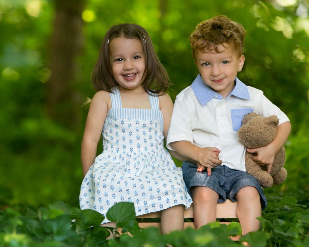 Young twins smiling together during outdoor Watch Me Grow photography session.