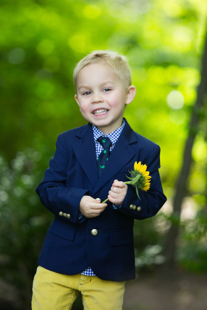 Young boy holding a sunflower during an outdoor portrait session near the studio.