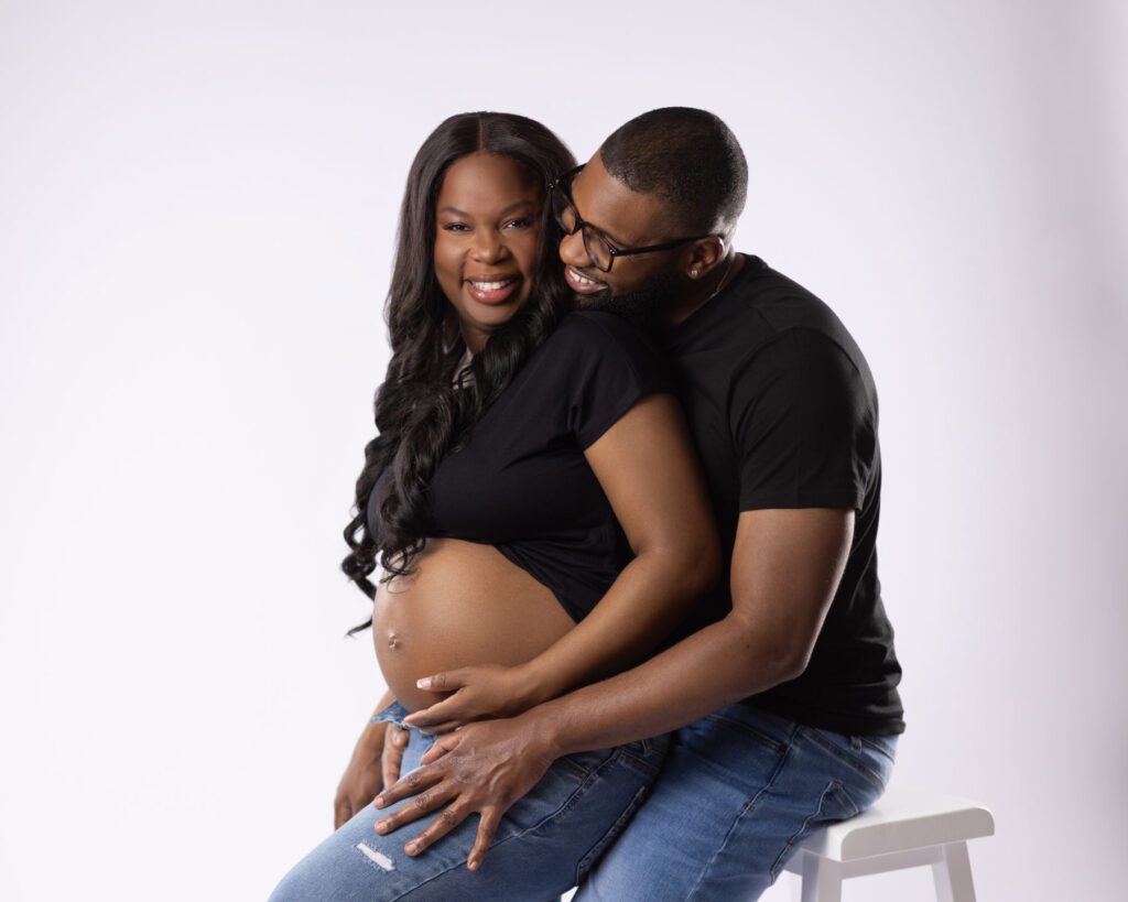 Expecting couple sharing a joyful maternity portrait during a studio pregnancy session