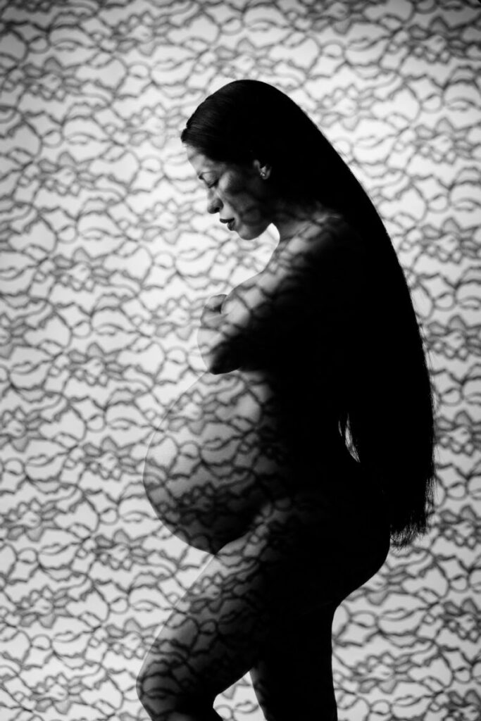 Artistic maternity silhouette portrait with lace shadow patterns and pregnancy profile