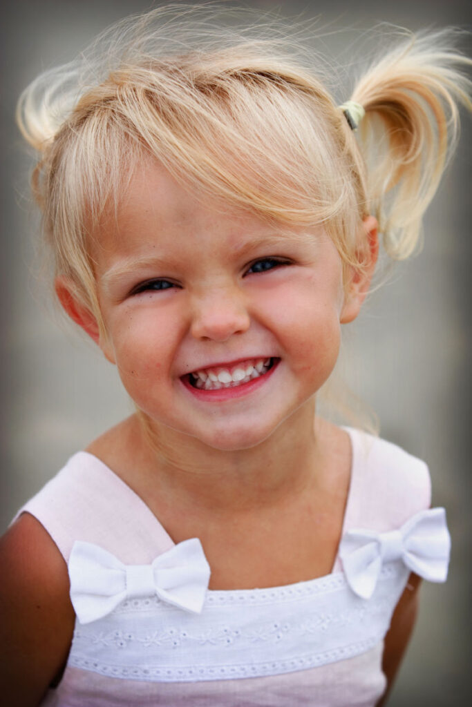 Smiling young girl with blonde pigtails during a child portrait session