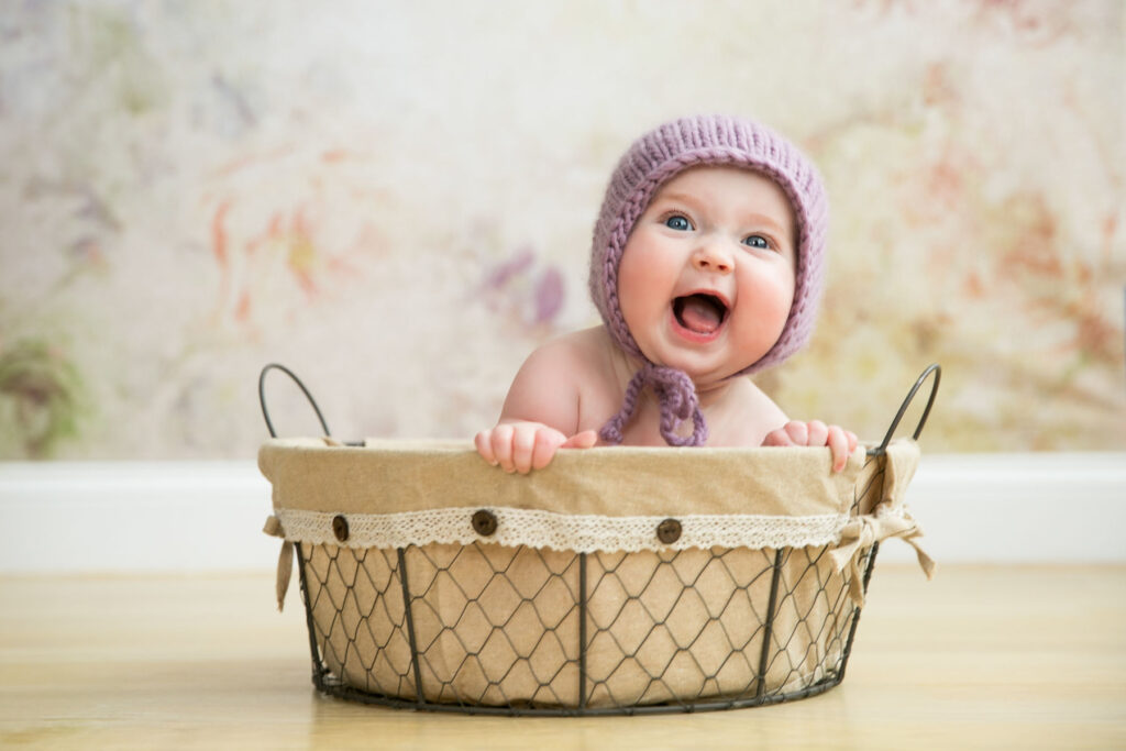 Smiling baby wearing a purple bonnet during a milestone portrait session
