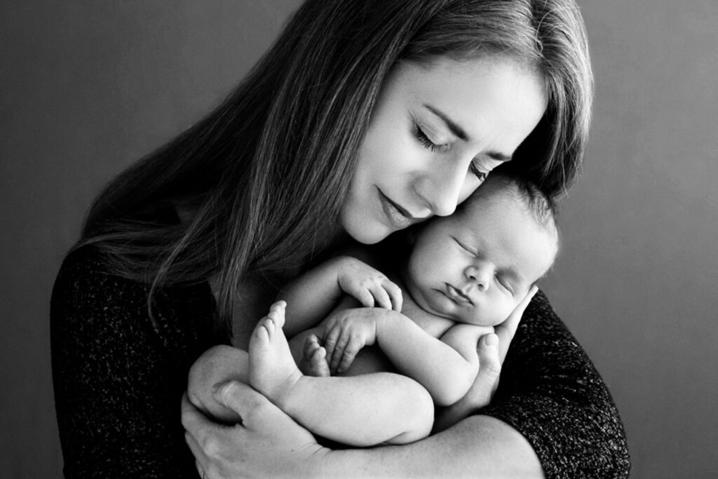 Mother holding her sleeping newborn in a timeless black-and-white portrait