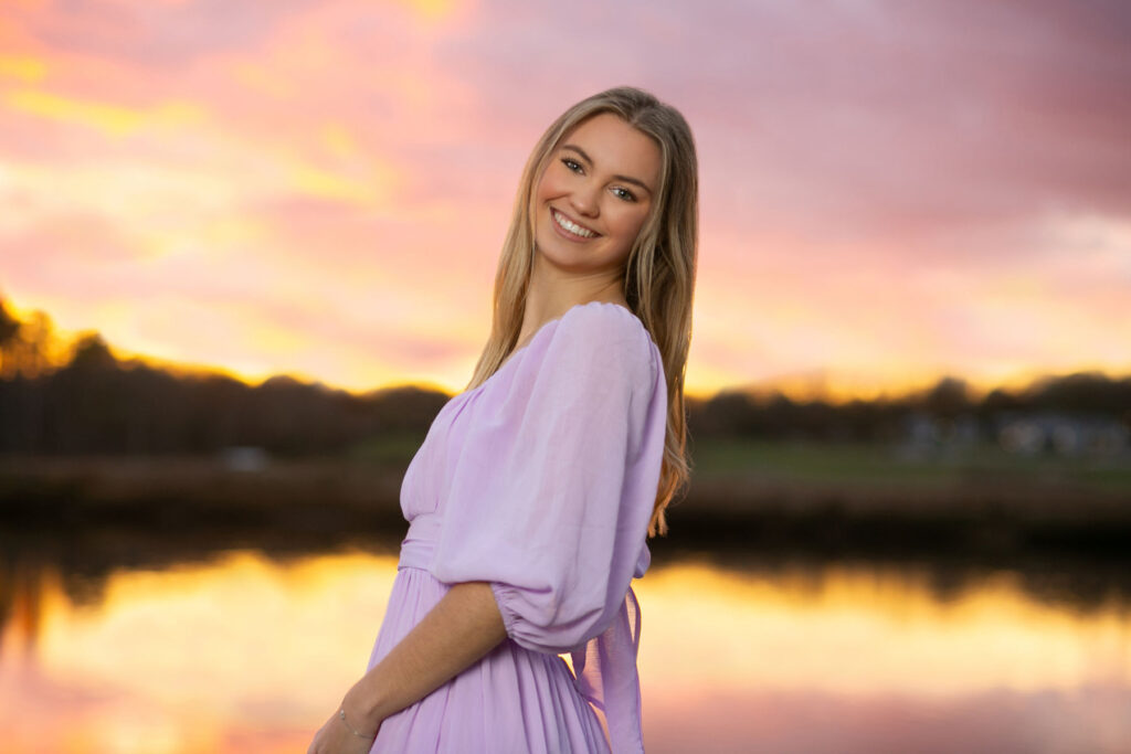 High school senior smiling during an outdoor portrait session at sunset