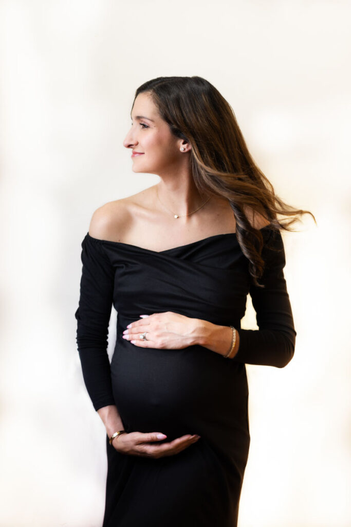 Expecting mother in a black dress during a studio maternity portrait session