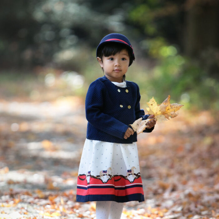 Toddler girl holding autumn leaves during outdoor fall child photography session in natural light