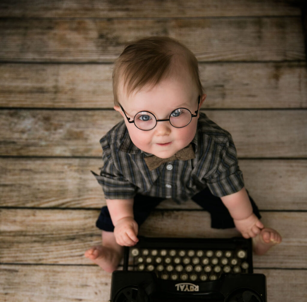 Baby boy wearing round glasses and a bow tie during a vintage-themed sitting milestone photography session in Norwood, MA