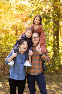 Family of four smiling together during an outdoor fall family photography session in Norwood, Massachusetts