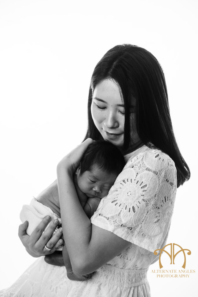 Japanese mother holding newborn baby in black-and-white Boston studio portrait