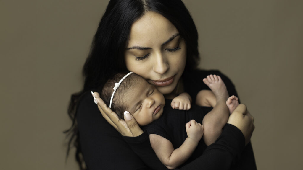 Mother holding her sleeping newborn daughter during a newborn photography session at Alternate Angles Photography in Boston MA