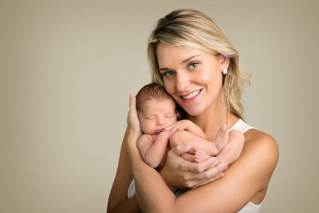 New mother holding her sleeping newborn baby during a professional newborn photography session in Massachusetts