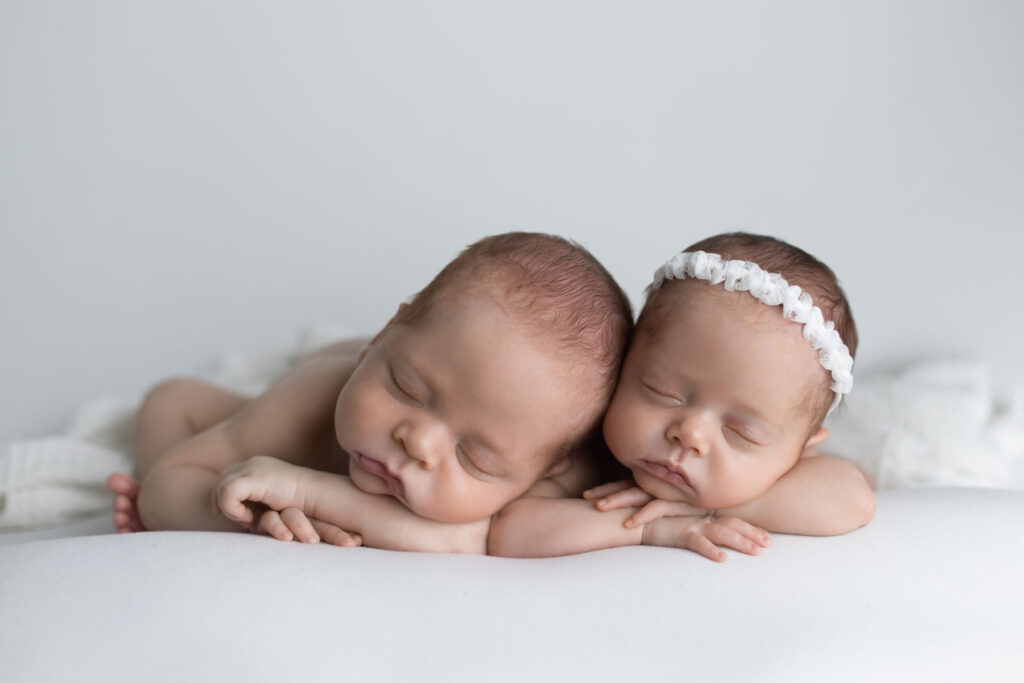 Sleeping newborn twins posed together during a professional newborn photography session in Massachusetts