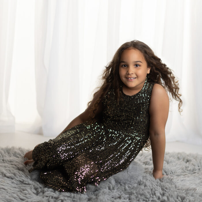 6 year old girl wearing a black sparkle dress posing during a professional child photography studio session