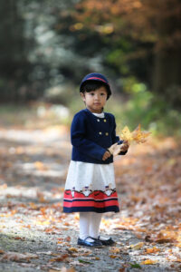 Young girl holding autumn leaves during an outdoor child photography session in Norwood, MA