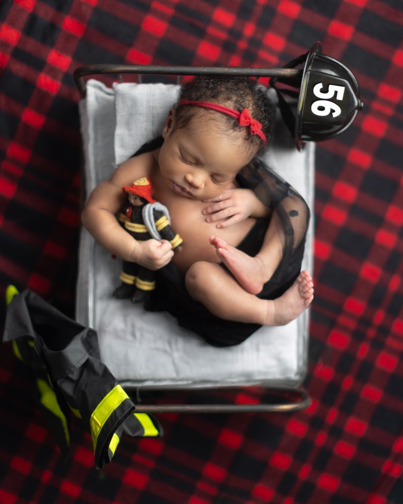 Newborn baby sleeping in a firefighter-themed setup during a Boston newborn photography session.