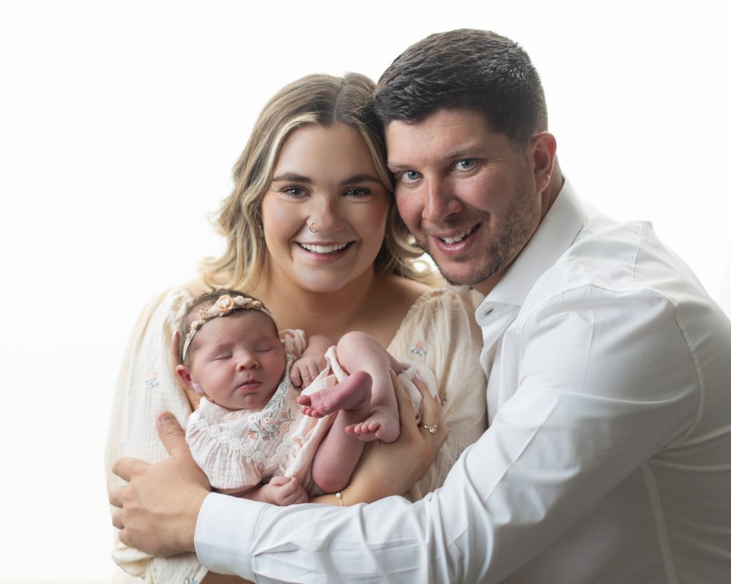 Boston newborn photographer family portrait with parents holding their newborn baby girl during a studio photography session.