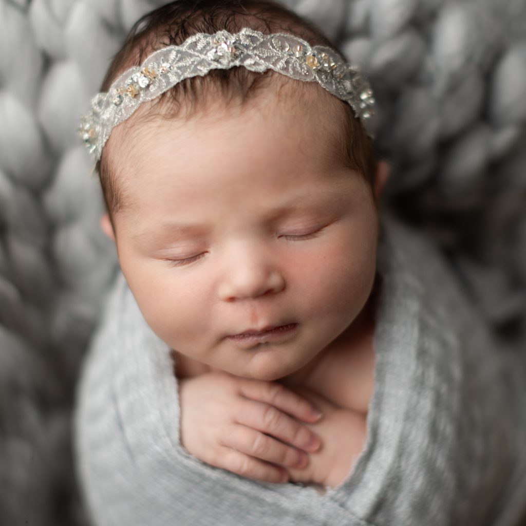 Greater Boston newborn photography close-up portrait of a sleeping newborn baby girl wearing a delicate lace headband.