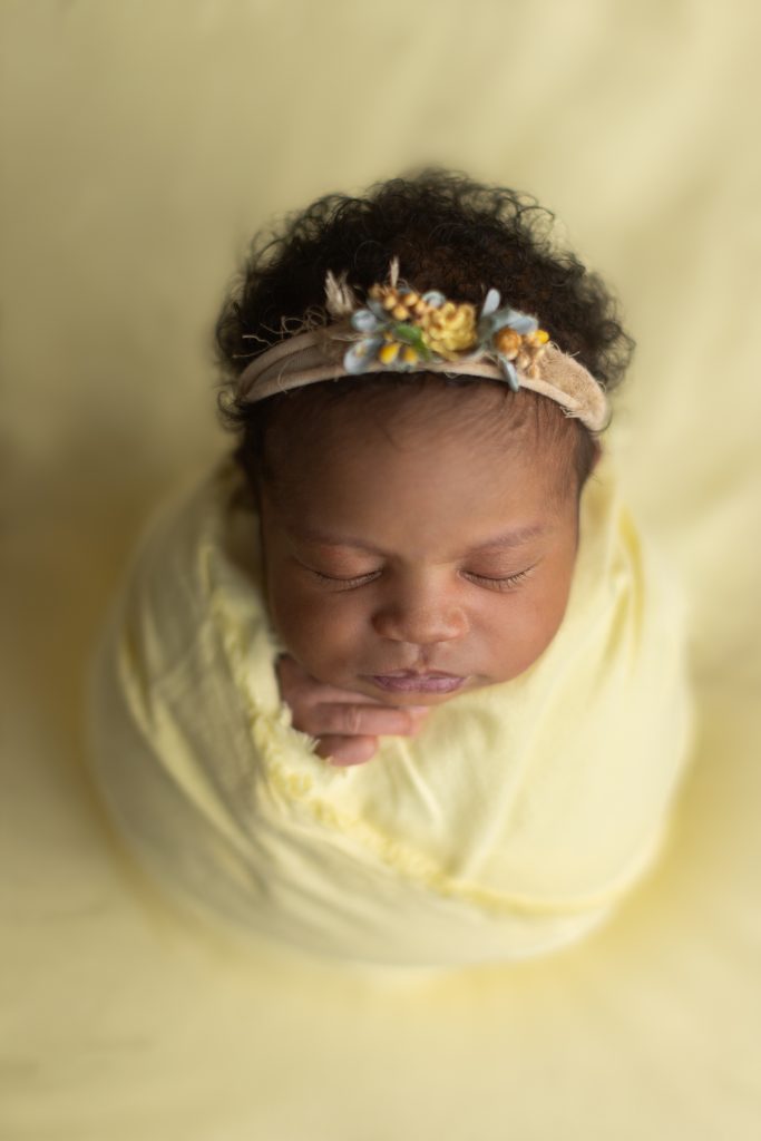 Newborn baby girl wrapped in yellow during a gentle Boston newborn photo session.