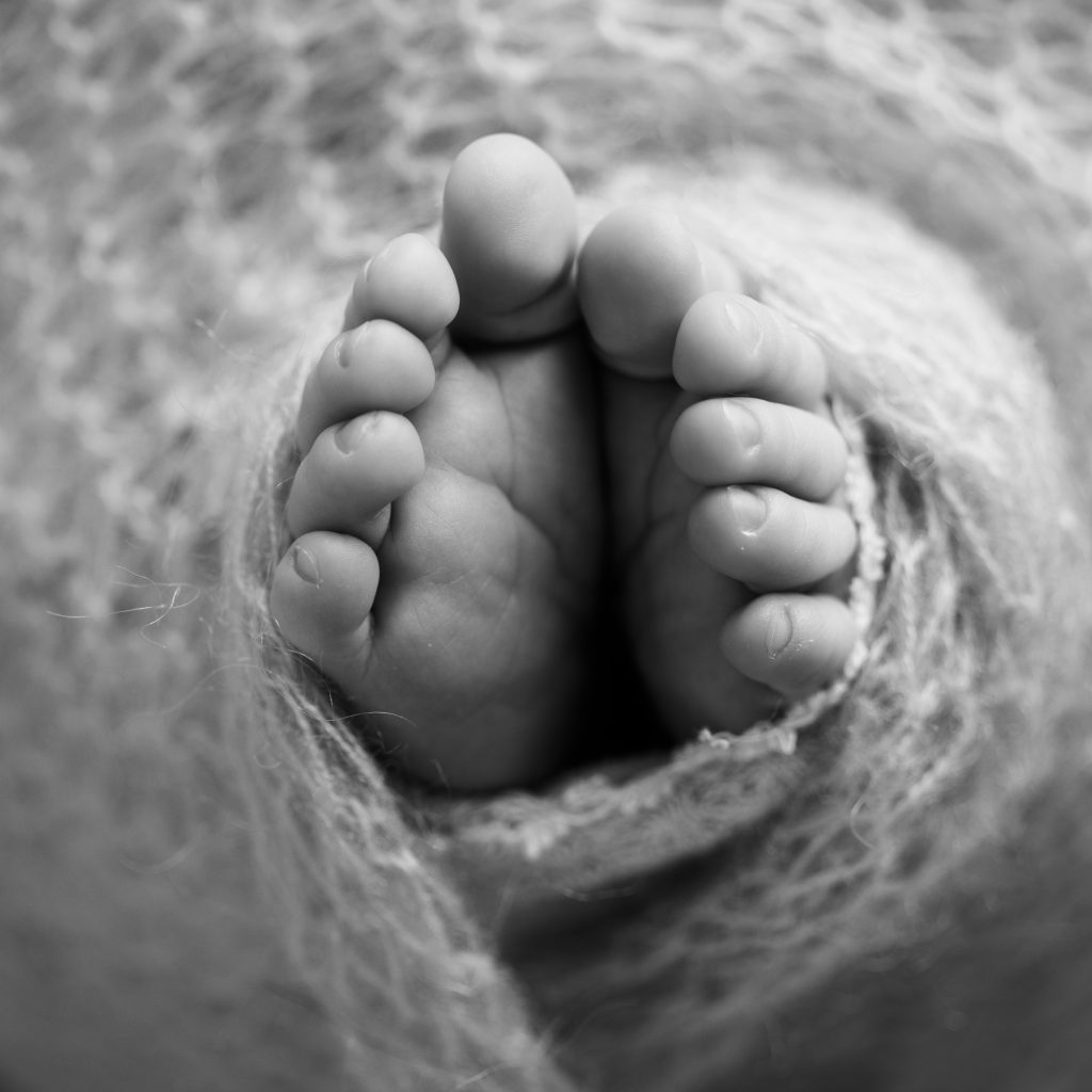 Black-and-white close-up photograph of a newborn baby's tiny feet