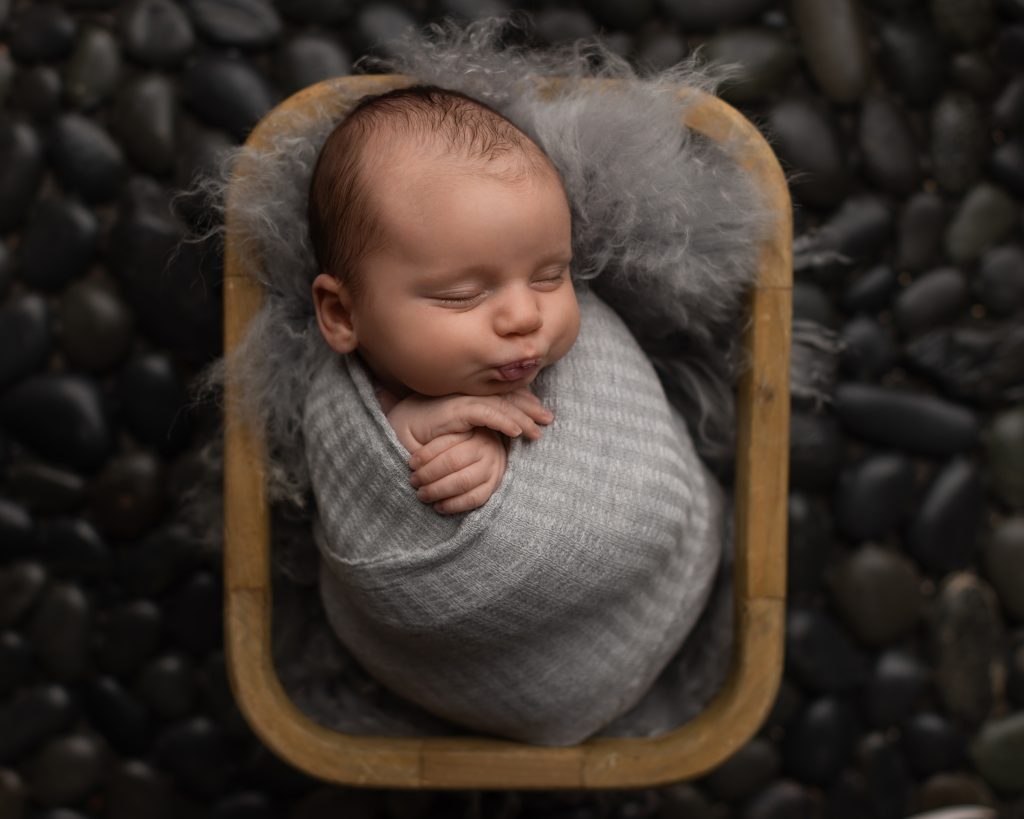 Sleeping newborn baby wrapped in gray during a Norwood MA newborn photography session