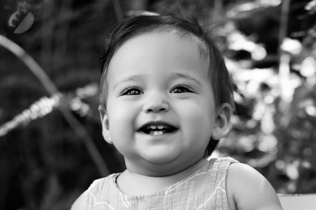 Black-and-white close-up of a smiling baby during a first-year milestone photography session.